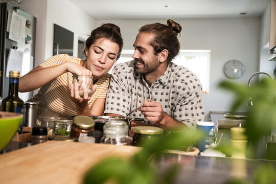 Smiling woman cooking food with man in kitchen at home