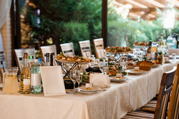 Elegant Wedding Reception Table Setting with Food, Wine, and Lush Garden View. Cream Linen, Glassware, and Fine Dining Atmosphere