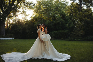 Two brides share an intimate moment outdoors during golden hour