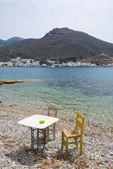 Table with chairs on the beach in Xilokeratidi, facing the Katapola harbor. Amorgos, Cyclades, Greece