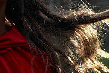 woman is captured with her long hair gently blowing in the breeze while wearing a striking red...