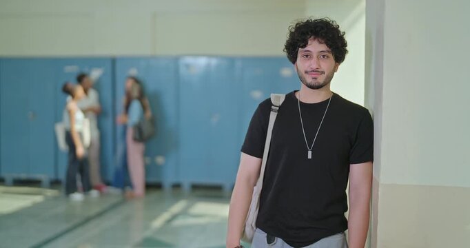 Indian young adult gen z proud smart boy look camera cross arm standing indoor campus place. Happy teen pupil male man wear bag fold hand staring cam do casual pose enjoy new good day college area