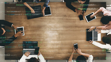 A diverse group of professionals collaborates at a modern workspace, engaging with various digital devices while coding elements enhance the tech-inspired atmosphere. Xenic