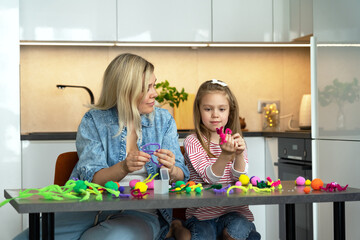 Happy family make diy from colored chenille wire toys. Mother and little daughter create handmade craft. Leisure with children