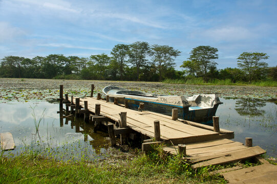An old wooden dock and a rustic fishing boat resting on a calm lake.