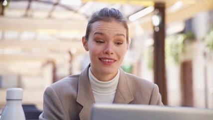 A focused young woman is diligently working on her laptop in a sleek and modern workspace
