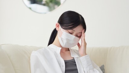 風邪を引いて咳をするアジア人女性