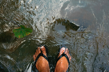 feet with flip flop submerged in the river flow