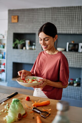 Happy young woman  having fun preparing healthy lunch food chopping vegetable  in kitchen