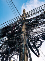 Dangerous overloaded utility pole with excessive tangled electrical wiring and communication lines...