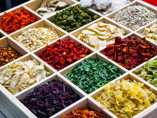 Colorful array of dried herbs and spices displayed in a wooden box at a local market