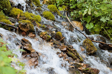 dettagli dell'acqua che scorre tra le rocce, in un ruscello di montagna, di giorno, in estate