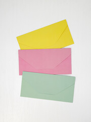 Three pink, yellow and green closed envelopes for money on white background, message concept