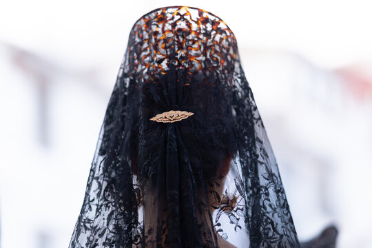 Peinado de mujer con peineta y mantilla negra y dorada en la cabeza