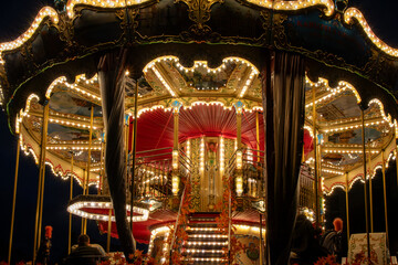 Beautiful two-level vintage carousel glowing with warm lights at night in Gdańsk, Poland