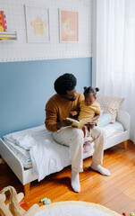 Father reads with daughter in cozy bedroom