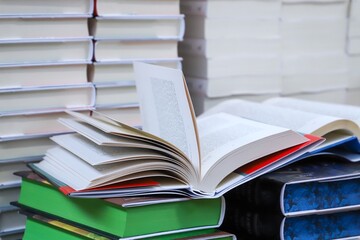 stack of books, close up. Open book on the table in library. Back to school concept. Open book on table with blur bookshelf background	