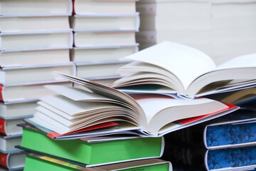stack of books, close up. Open book on the table in library. Back to school concept. Open book on table with blur bookshelf background	