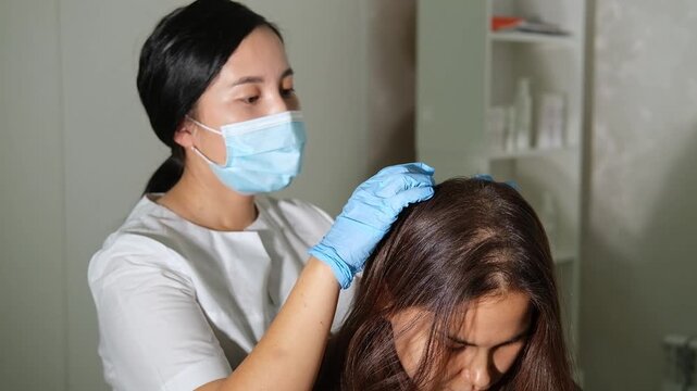 Examination of the scalp and hair by an asian trichologist doctor. 