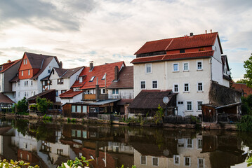 Obraz premium Cottages along the river in Eschwege, Germany, with reflections in the water under a bright sky
