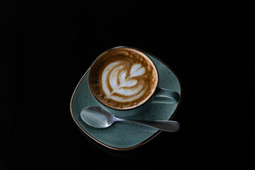 A cup of coffee with a frothy latte art heart on a wooden table