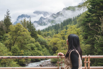 happy woman tourist trekking at mountain in Changping valley near Siguniang mountain in Sichuan province, China, color effect, low key and soft focus.