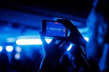 Person recording concert video on smartphone