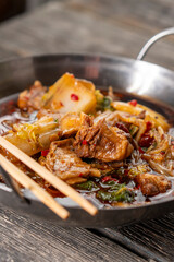 Sichuan lamb ribs with Chinese cabbage. Meat in an iron bowl on a wooden background. Chinese cuisine. Food concepts.