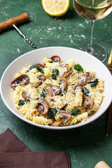 Pasta in a creamy sauce with mushrooms, spinach, and cheese. Italian cuisine. Vegetarian food.