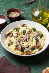 Pasta in a creamy sauce with mushrooms, spinach, and cheese. Italian cuisine. Vegetarian food.
