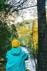 A female tourist looking at a mountain river against the backdrop of an autumn landscape, hiking in the mountains