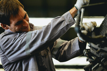 White man technician checking used car damaged engine block at scrap yard warehouse recycle area...