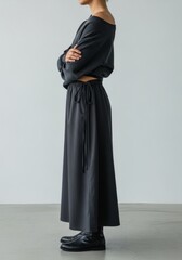 Woman in dark gray outfit with arms crossed side view shot