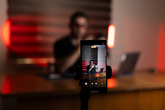 The person is recording a podcast or a video stream using a smartphone set up  - Powered by Adobe