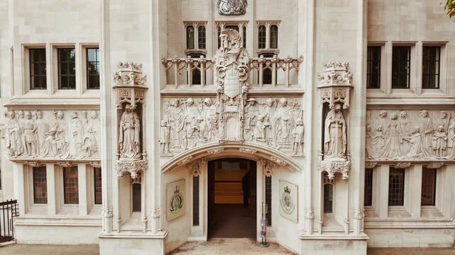 The Supreme Court in London, England, UK, showing carved stone, arched windows and civic emblems by Parliament Square