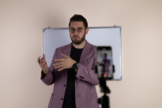 Man is recording a video for his blog using a smartphone mounted on a tripod