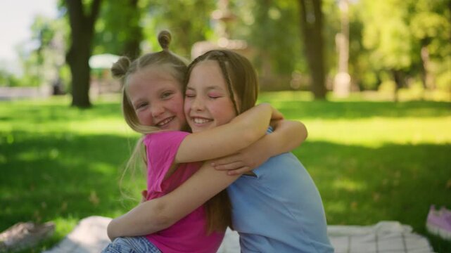 Portrait of happy siblings talking and hugging each other in sunny urban park