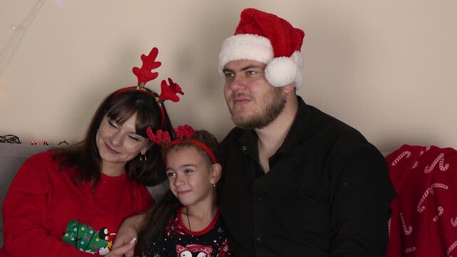 The family is posing together for a festive Christmas photo,wearing holiday acc
