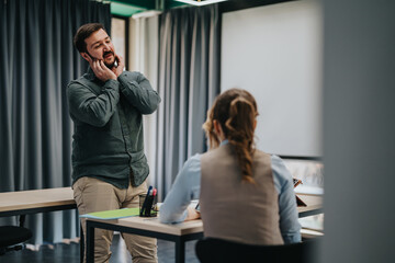 A man interacts with a woman during a discussion in a contemporary office space. The image conveys...
