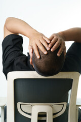 Stressed businessman leans back in chair with hands on head seeking relief from work pressures now