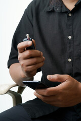 Man enjoys modern tobacco alternative while using his smartphone in a relaxed casual setting
