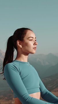 Vertical slow motion video of woman raising arms from Namaste pose during sunrise, symbol of strength, mindfulness and spiritual growth