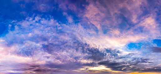 Sunset over calm river shore panoramic view. Dramatic sunset violet dark. Yellow Orange blue color shades cloudy sky. A strip of forest silhouette fills horizon line.