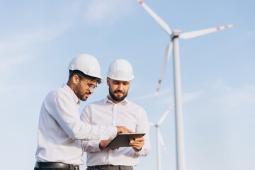 Engineers using tablet working in wind turbine power plant