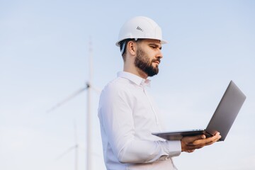 Engineer working with laptop analyzing wind turbine data for sustainable energy production