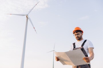 Arabian engineer reading blueprint in a wind turbine power plant