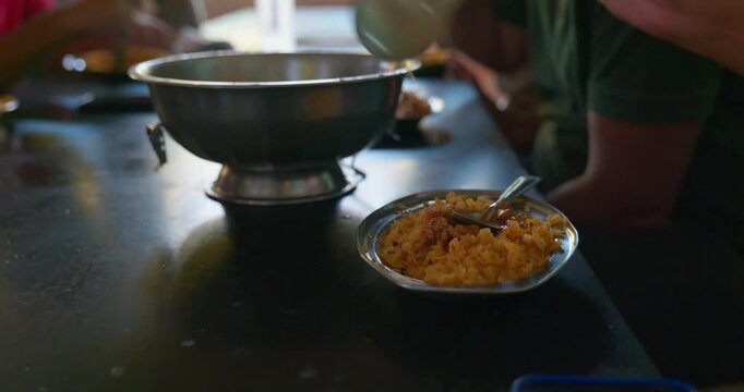 Customer serving poha with spicy rassa by hand in village roadside hotel, authentic Indian breakfast experience