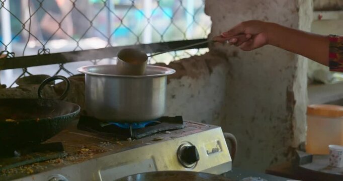 Making and straining hot Indian tea into paper cups without handle at roadside tea stall