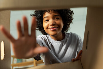 Inside of cardbox bottom view. African girl unpacking delivery looking in box. Woman opening carton...