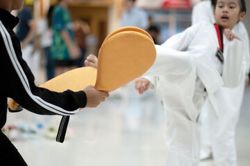 Asian boy and girl athletes practicing Taekwondo while waiting for the competition. Boy holds a kick pad targets for a girl to kick. Training or exercise with Taekwondo sport